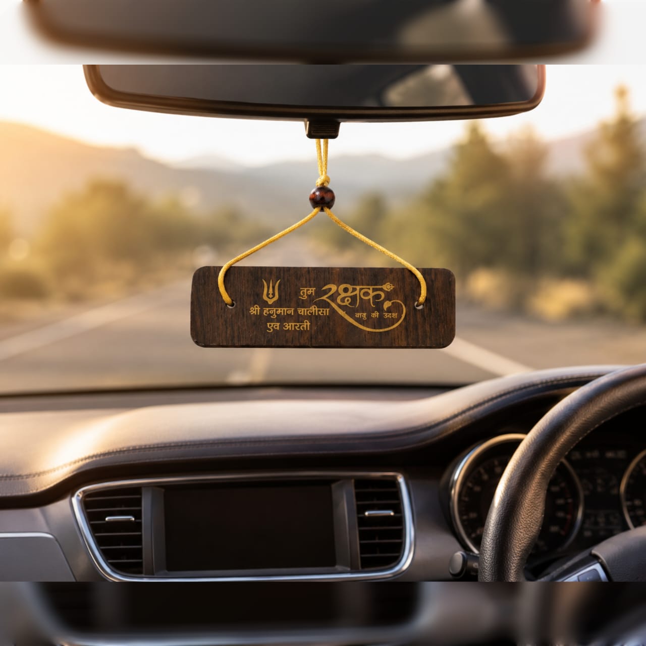 Car dashboard with a hanging wooden plaque displaying text and symbols.