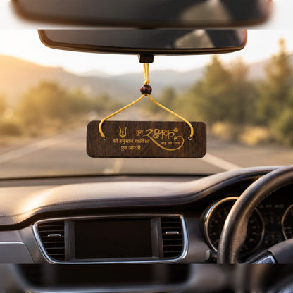 Car dashboard with a hanging wooden plaque displaying text and symbols.
